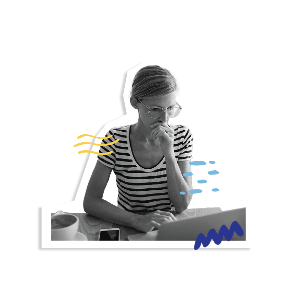 A person wearing large glasses and a striped, short-sleeved t-shirt is looking intently at their laptop.